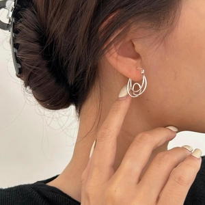 Close-up of minimalist silver multi-layered knot earrings worn by a model