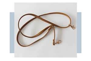 Close-up of adjustable brown leather shoulder strap with gold metal hooks and buckles