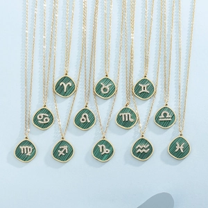Macro view of gold necklaces with green malachite zodiac pendants and sparkling crystals
