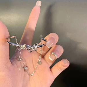 Detail of silver butterfly bracelet with tassel chain on a hand with elegant manicure