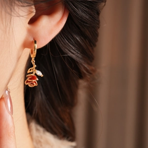 Détail d'une boucle d'oreille fleur en émail rouge vintage avec base dorée et zircon
