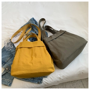 Detail view of lightweight nylon handbags in mustard yellow and army green for casual wear