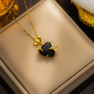 Detail shot of a black heart pendant with gold star accents on a gold chain necklace