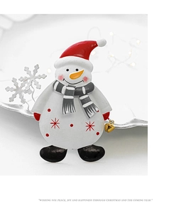 Macro shot of snowman brooch with red hat and engraved holiday greeting text