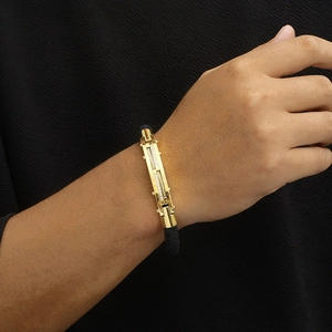 Detail of gold metal buckle with pavé crystals and black cable cord on the wrist