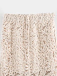 Gros plan sur la taille d'une jupe en maille beige montrant la dentelle complexe