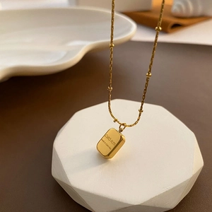 Vintage gold square pendant necklace made of titanium steel on white geometric stand