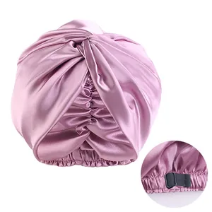 Detail of pink satin sleep cap with twisted front and black adjustable buckle strap