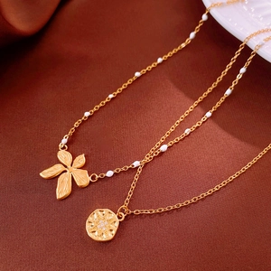 Detail of double-layer gold necklace with flower pendant and white beads on silk