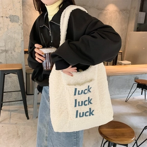 Close-up of winter fleece tote bag with blue luck embroidery and soft lambskin texture