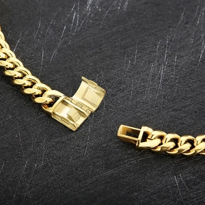 Hip hop gold Cuban link chain necklace with polished box clasp detail on black surface
