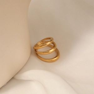 Minimalist triple-layered gold stainless steel ring set on a soft silk background