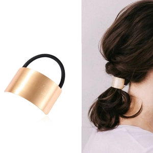 Detail of gold curved metal hair clip with black elastic band on model and product view