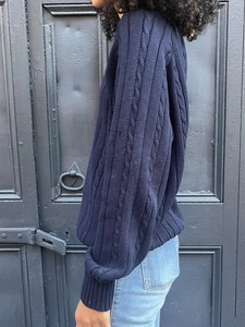 Detail of dark blue cable knit sweater featuring classic textured patterns and loose fit