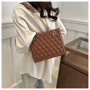 Close-up of brown quilted rhombus chain tote bag with elegant gold metal straps