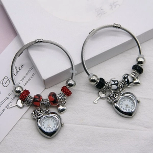 Detail of silver beaded bracelets featuring heart-shaped watch pendants and key charms