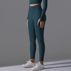 Detail of high-waist seamless dark teal yoga leggings and long sleeve top with thumbholes
