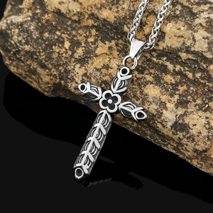 Vue détaillée d'un pendentif croix en argent avec motifs floraux sur une texture roche