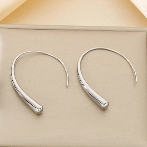 Close-up of minimalist silver curved line earrings on a beige jewelry cushion