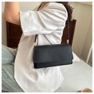 Detail of black woven shoulder bag with intricate Intrecciato texture on model