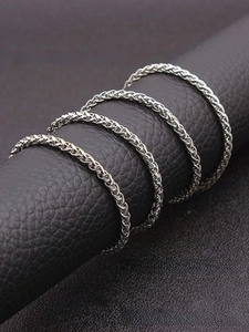 Detailed macro view of four silver woven wheat chain rings for men in stainless steel