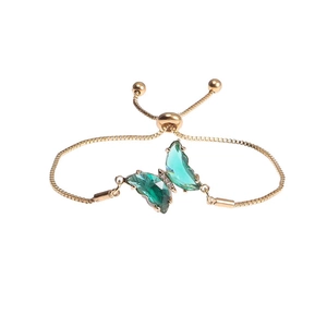 Detail view of adjustable gold-tone bracelet with green crystal butterfly and slider clasp