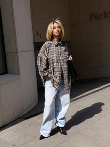 Street style shot of grey plaid long-sleeve shirt paired with loose light blue denim jeans