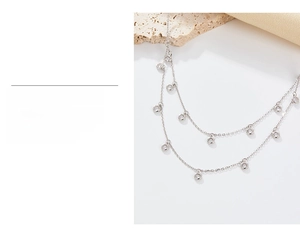 Detail of double-layer silver necklace with shiny cubic zirconia stones on textured fabric