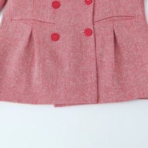 Detail of red herringbone wool coat featuring double-breasted buttons and fabric texture