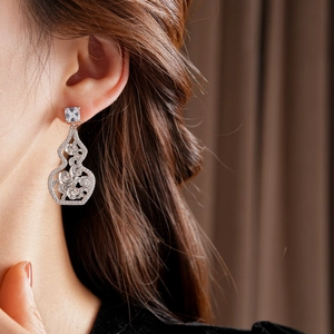 Close-up of a silver hollow gourd earring with sparkling zircons worn by a model