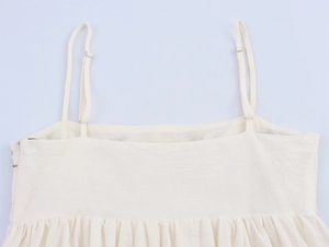 Detail of adjustable spaghetti straps and pleated bust on ivory vacation mini dress