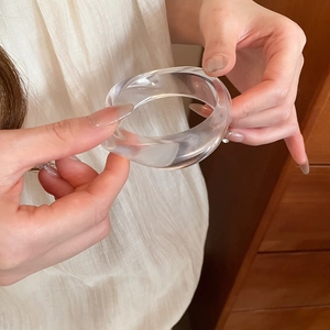 Close-up of a minimalist acrylic resin bangle showing smooth texture and light reflection