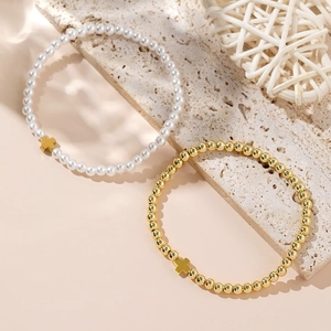 Detail of white pearl and gold beaded bracelets featuring elegant cross pendants