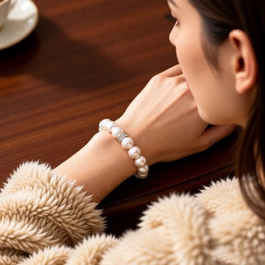 Detail of elegant pearl bracelet with crystal spacers worn over a faux fur coat cuff