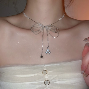 Close-up of silver crystal beaded bow necklace with heart pendant on a model's neck