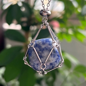 Close-up of a blue natural stone pendant secured in a silver mesh cage necklace