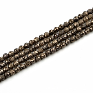 Macro detail of faceted pyrite beads showing metallic luster and precise cut texture