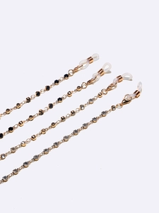 Golden eyewear chains set with black and clear rhinestones on white background