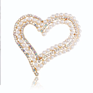 Detail of heart-shaped gold brooch with white pearls and iridescent rhinestones