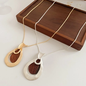 Close-up of teardrop wood and metal pendant necklaces on a wooden tray