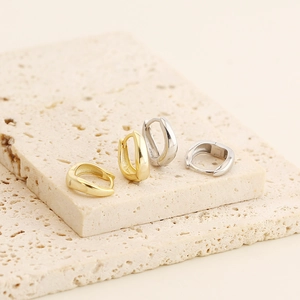 Detail view of gold and silver irregular U-shaped geometric earrings on stone