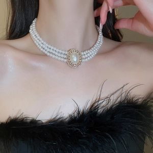Three-layer faux pearl necklace featuring an ornate vintage gold pendant with crystals