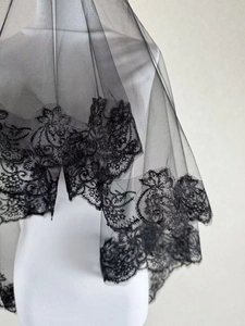 Close-up of black mesh bridal veil with intricate floral lace trim and leaf patterns