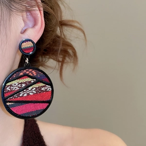 Close-up of Bohemian geometric drop earrings with woven ethnic pattern and black frames