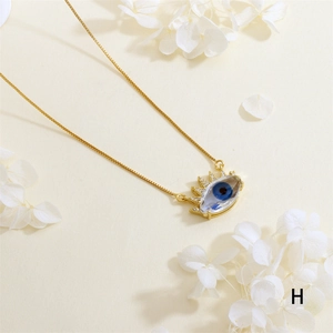 Detailed close-up of a gold-plated evil eye pendant with blue resin and zircon accents