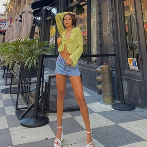 Green ruffle tie-front deep V-neck sheer top paired with a denim mini skirt in street style