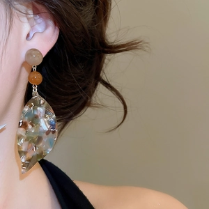 Side view of tortoise shell pattern leaf drop earring worn on a model with beige beads