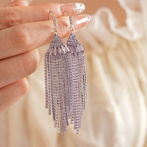 Detailed macro view of purple rhinestone tassel earrings with silver metal hooks