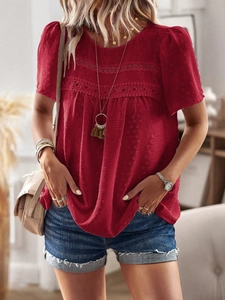 Close-up of red crewneck top showing lace patchwork and Swiss dot texture detail