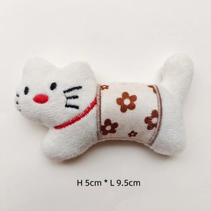 Macro view of white plush cat brooch with floral fabric detail, size 9.5cm length by 5cm high